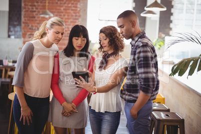 Woman showing digital tablet to young friends at coffee shop