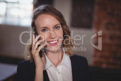 Portrait of smiling young beautiful female editor talking on cellphone