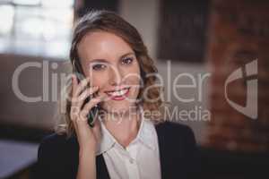 Portrait of smiling young beautiful female editor talking on cellphone