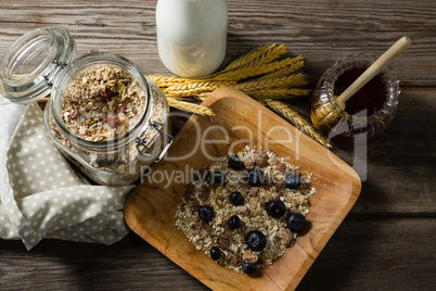 Breakfast cereals and jar of honey on wooden table