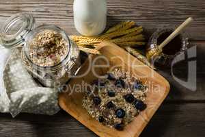 Breakfast cereals and jar of honey on wooden table