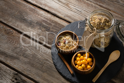 Bowl of cape gooseberry and jar of muesli on table