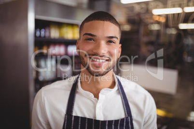 Smiling handsome young waiter at coffee shop