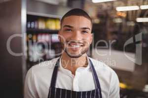 Smiling handsome young waiter at coffee shop