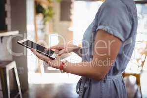 Midsection of woman scrolling digital tablet