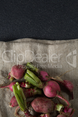 Overhead view of red radishes on burlap