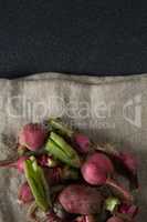 Overhead view of red radishes on burlap