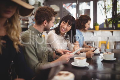 Smiling young friends talking while sitting at table