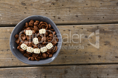 Chocolate cornflakes with honeycomb cereal forming smiley face in bowl