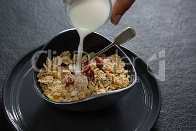 Milk being poured into wheat flakes bowl