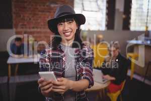 Portrait of smiling young woman using mobile phone at coffee shop