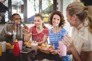 Young friends talking while sitting at cafe