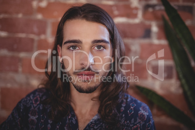 Close up portrait of confident young male photographer against brick wall