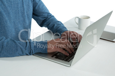 Mid-section of man using laptop at desk Mid-section of man using laptop at desk