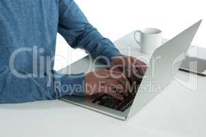 Mid-section of man using laptop at desk