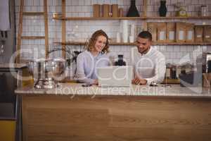 Young waitress and male owner using laptop at counter