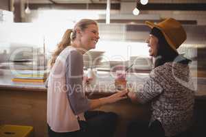 Cheerful female friends talking while sitting at coffee shop