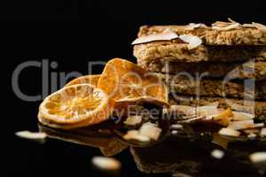 Granola bars with dried coconut and orange slices on black background