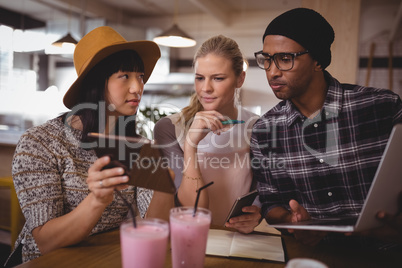 Young woman showing digital tablet to friends at coffee shop