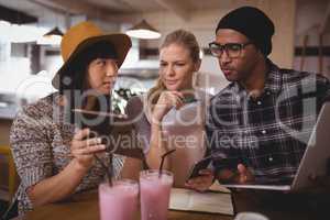 Young woman showing digital tablet to friends at coffee shop