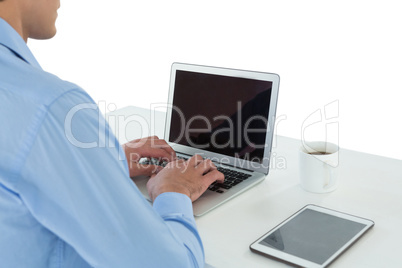 Businessman using laptop by tablet computer at table