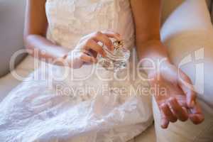 Midsection of bride spraying perfume on hand