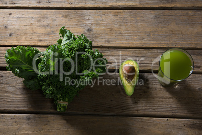 Mustard greens, avocado and juice on wooden table