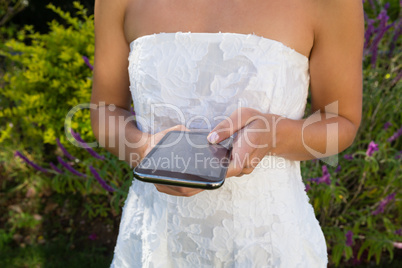 Midsection on bride using smart phone while standing in yard