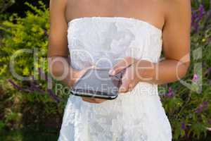 Midsection on bride using smart phone while standing in yard