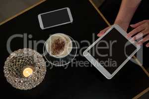 Overhead of woman using digital tablet while having coffee