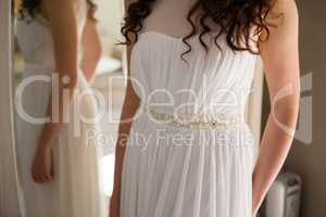 Midsection of bride in wedding gown standing by mirror