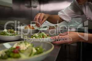 Female chef garnishing appetizer plates at order station