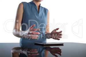 Mid section of businesswoman gesturing over digital tablet at table