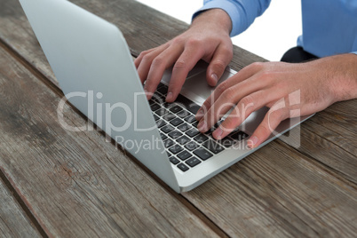 Cropped image of businessman using laptop at wooden table