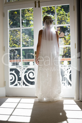 Rear view of bride in wedding dress standing by door