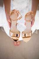 Low section of bride holding sandals while sitting in fitting room