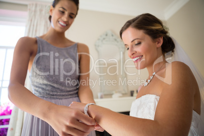 Bridesmaid assisting bride in getting dressed at fitting room