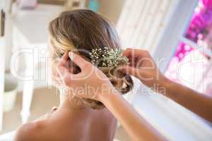Cropped hands of bridesmaid adjusting bride hair in room