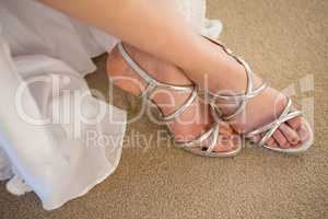 Low section of bride wearing silver sandals at home