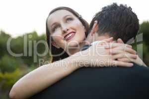 Happy newlywed couple embracing while standing in park