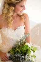 High angle view of smiling bride holding bouquet while sitting on bed