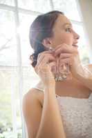 Low angle view of beautiful bride wearing earring while standing by window