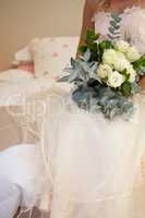 Midsection of bride in wedding dress holding bouquet on bed