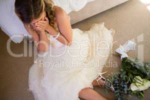 High angle view of bride in wedding dress crying while sitting by bed