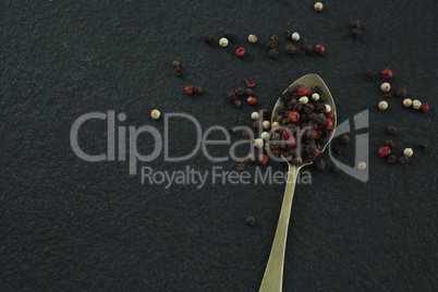 Black pepper and white pepper seeds in a spoon