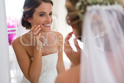 Bride looking into mirror while standing in fitting room