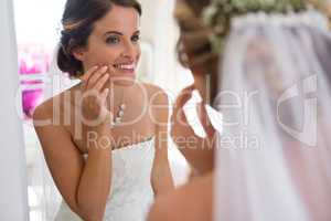 Bride looking into mirror while standing in fitting room