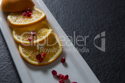 Slice of orange with pomegranate seeds in tray