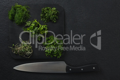 Various herbs on chopping board with knife