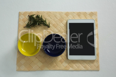 Rosemary and empty bowls with digital tablet on place mat
